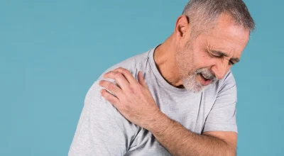 Foto colorida de homem com blusa branca com osteoartrite no ombro - Metrópoles.