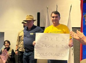 Flávio Bolsonaro (PL-RJ) levanta cartaz escrito "o Pix é do Brasil e do Bolsonaro", em Contagem, Minas Gerais. Foto: reprodução / rede x